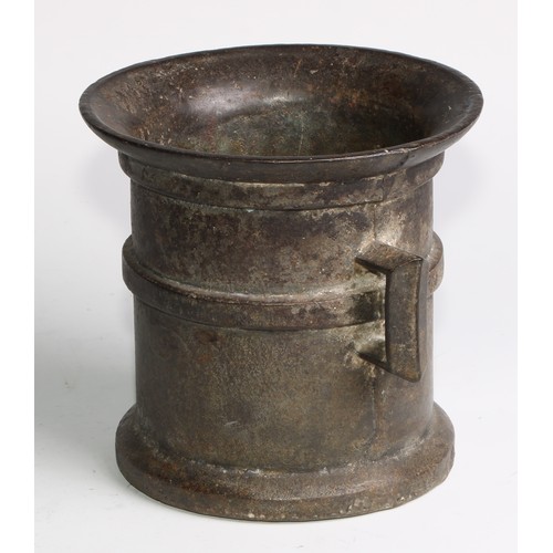 1679 - A cast iron pestle and mortar, flared rim above a quarter girdle, angular lug handles, skirted base,... 