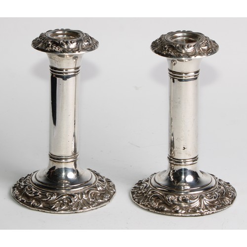 1016 - A pair of Edwardian silver candlesticks, leafy scroll borders, 16cm high, Birmingham 1906