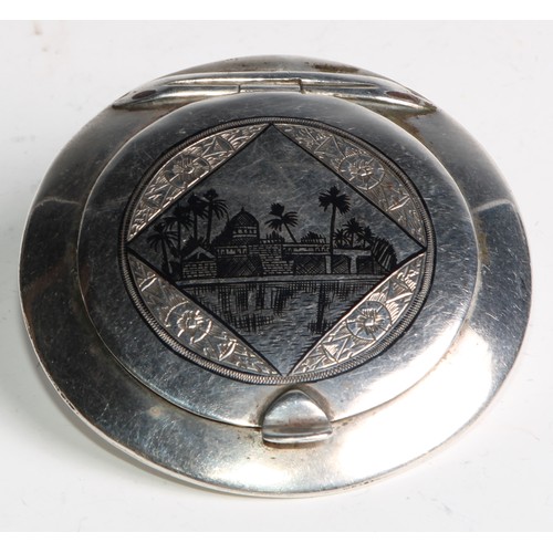 1189 - An Iraqi silver and niello circular compact,  hinged cover decorated with a desert scene, to verso w... 