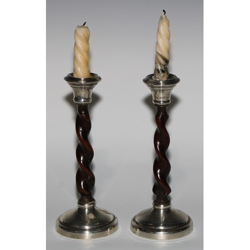 1010 - A pair of Arts and Crafts silver and oak candlesticks, spirally turned pillars, domed circular bases... 