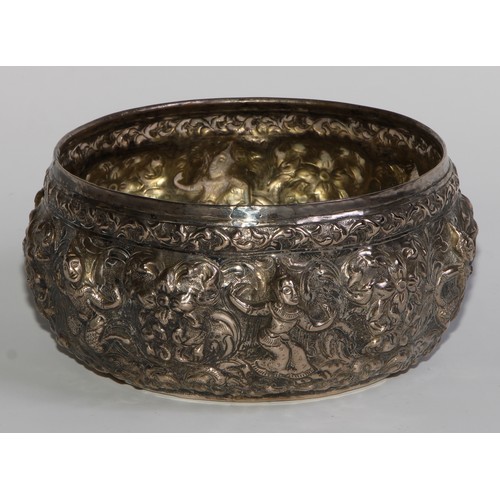 850 - A 19th century Burmese silver circular bowl, repousse chased with deities and scrolling foliage, gil... 