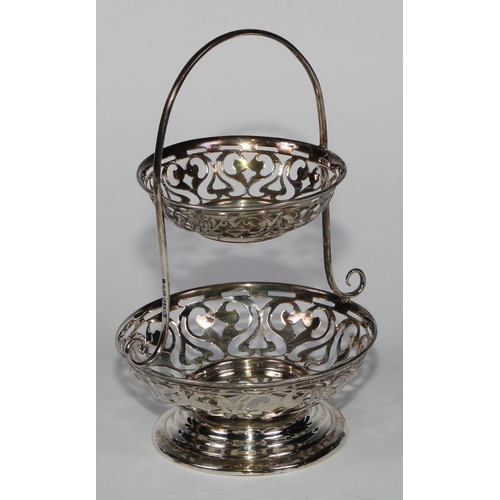 979 - A George V silver two-tier sweetmeat waiter, pierced with scrolls, arched handle, stepped circular b... 