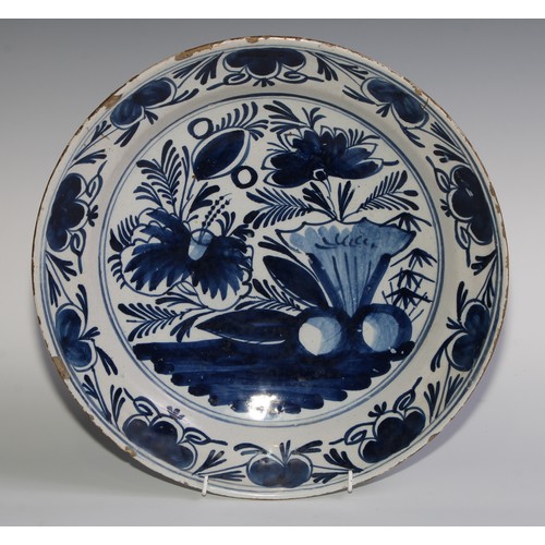 102 - An 18th century Delft circular charger, painted in tones of cobalt blue with flowers and fruit, 36cm... 