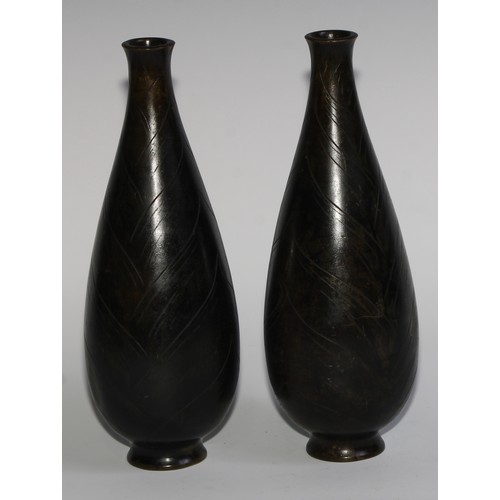 428 - A pair of Japanese dark patinated bronze slender ovoid vases, cast in shallow relief with lotus buds... 