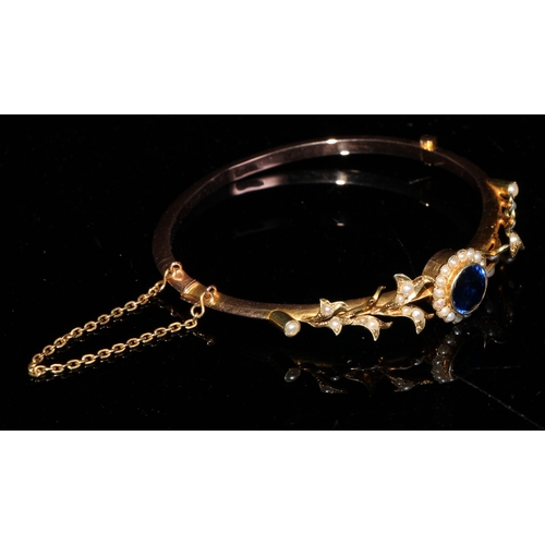 1404 - A late 19th/early 20th century 15ct gold hinged bangle bracelet, set with a central synthetic sapphi... 