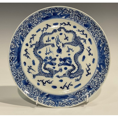 360 - A Chinese circular dish, painted in tones of underglaze blue with dragons chasing a flaming pearl, 2... 