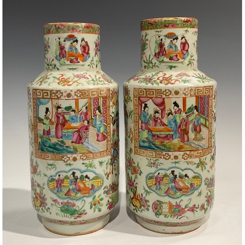 452 - A pair of Cantonese Famille Rose cylindrical vases, decorated with alternating shaped panels of Orie... 