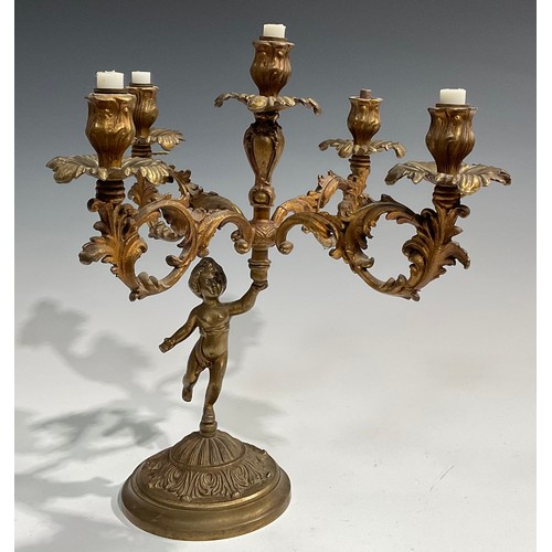 2093 - A pair of Rococo Revival gilt metal five light candelabra, each cast as a scantily clad putto holdin... 