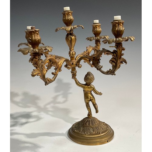 2093 - A pair of Rococo Revival gilt metal five light candelabra, each cast as a scantily clad putto holdin... 