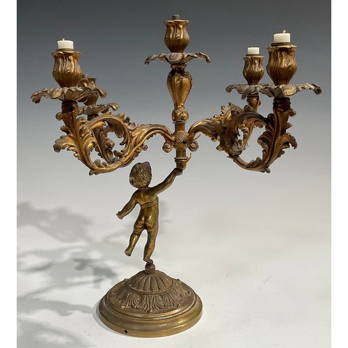 2093 - A pair of Rococo Revival gilt metal five light candelabra, each cast as a scantily clad putto holdin... 