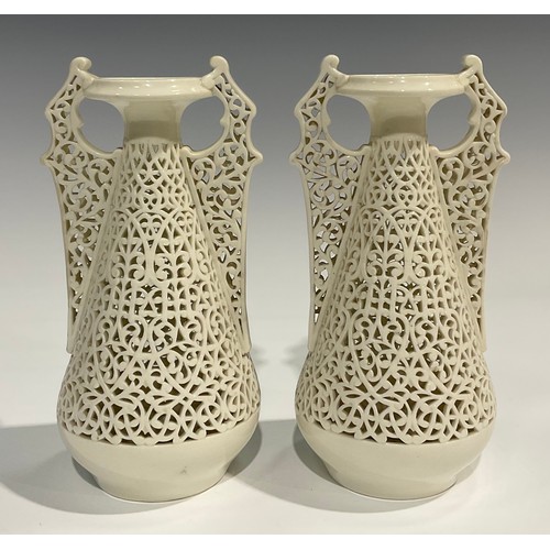 183 - A pair of Graingers Worcester reticulated spreading ovoid vases, in the white, with Persian inspired... 