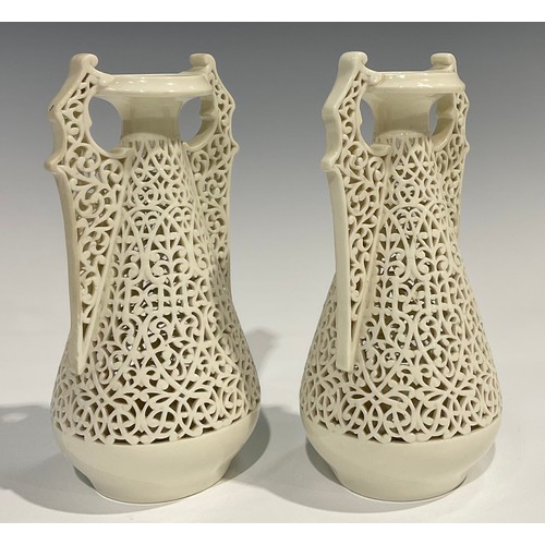 183 - A pair of Graingers Worcester reticulated spreading ovoid vases, in the white, with Persian inspired... 