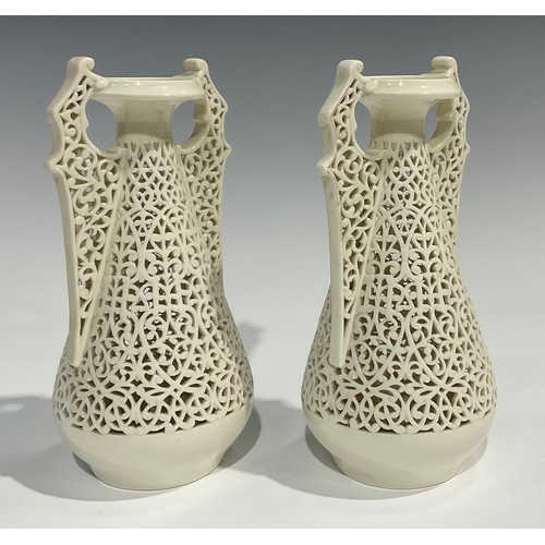 183 - A pair of Graingers Worcester reticulated spreading ovoid vases, in the white, with Persian inspired... 