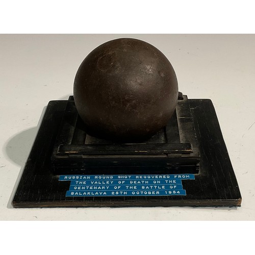 1558 - A 19th century cast iron cannonball, the collector’s stand with label inscribed Russian round shot r... 