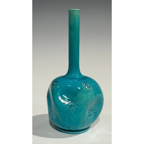 27 - A Burmantofts Faience bottle vase, dimpled globular body, applied with sgraffito sunbursts, long cyl... 