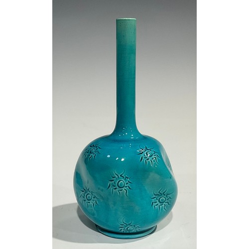 27 - A Burmantofts Faience bottle vase, dimpled globular body, applied with sgraffito sunbursts, long cyl... 