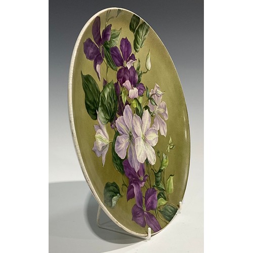 47 - A Howell & James Aesthetic Movement circular charger, painted by F M Minns, with clematis on a green... 