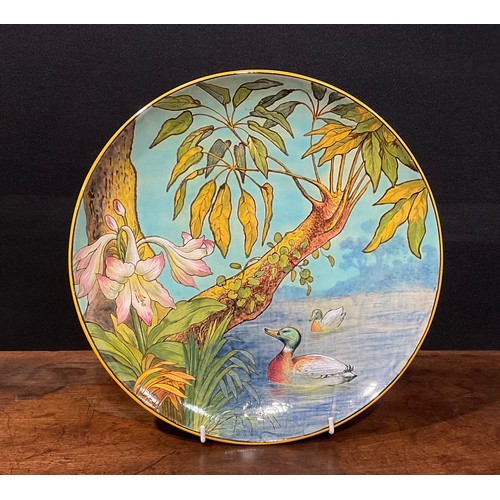 76 - An Aesthetic Movement circular charger, painted in polychrome with mallards at a riverbank, lilies a... 