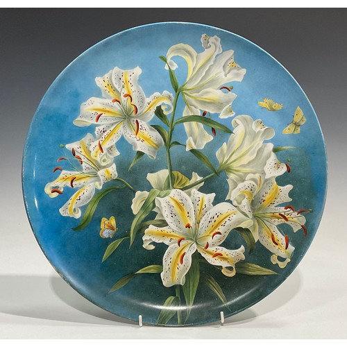 75 - An Aesthetic Movement circular charger, painted by M S Williams, with lilies on an ombre blue ground... 