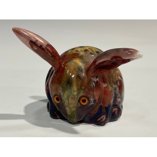 23 - A Bernard Moore lustre model, of a stylised long eared rabbit, glazed in mottled tones of mauve, pin... 