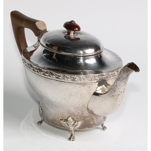 1139 - An Arts and Crafts silver three piece tea service, comprising teapot, hot water pot and sugar basin,... 