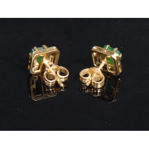 1433 - A pair of rectangular emerald solitaire ear studs, the cushion cut stone claw set within open work a... 