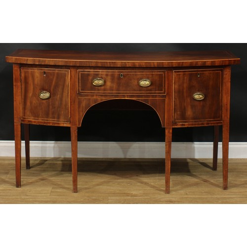 1786 - A George III mahogany bowfront sideboard or serving table, oversailing satinwood banded top above th... 