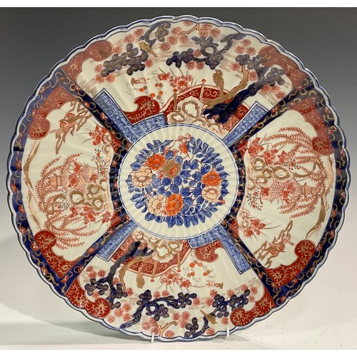 446 - A large Japanese fluted circular charger, decorated in the Imari palette with flowers, rockwork and ... 