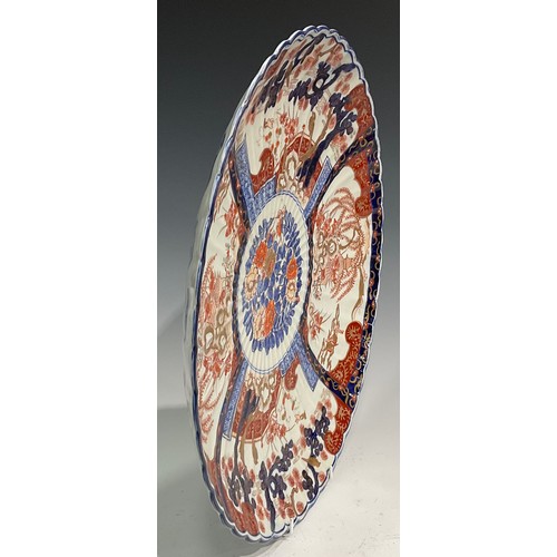 446 - A large Japanese fluted circular charger, decorated in the Imari palette with flowers, rockwork and ... 