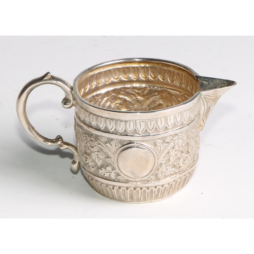 1092 - A Victorian silver milk jug and sugar bowl, repousse chased in the Indian taste with bands of geomet... 