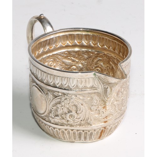 1092 - A Victorian silver milk jug and sugar bowl, repousse chased in the Indian taste with bands of geomet... 