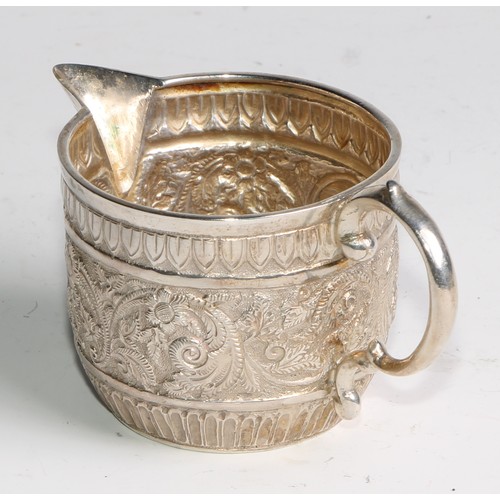 1092 - A Victorian silver milk jug and sugar bowl, repousse chased in the Indian taste with bands of geomet... 