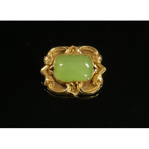 1411 - A mid 19th century shaped rectangular brooch, set with a single polished green cabochon, scrolls to ... 