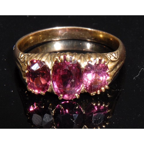 1470 - A Victorian style three stone ring, the graduated oval pink stones facet cut, yellow metal shank, si... 