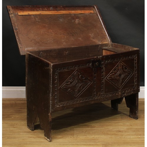 1568 - A 17th century elm six plank chest, hinged top enclosing a till, the front carved with leafy geometr... 