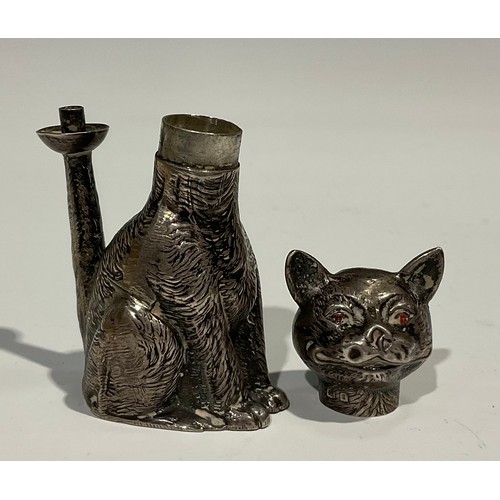 1155 - An Edward VII novelty table lighter as a grinning cat, 'Ruby' eyes, seated, the flame from his erect... 