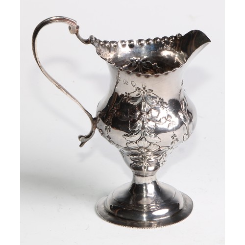 926 - A George III silver helmet shaped jug, embossed overall with flowering stems, beaded everted rim, do... 