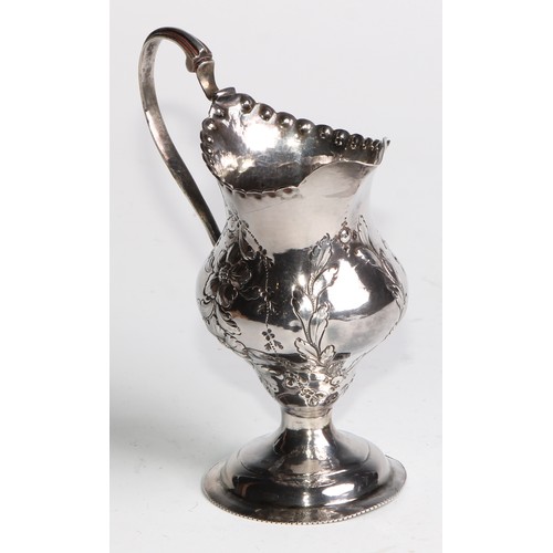 926 - A George III silver helmet shaped jug, embossed overall with flowering stems, beaded everted rim, do... 