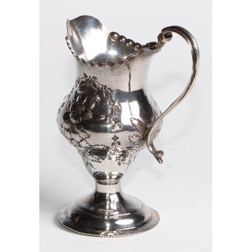 926 - A George III silver helmet shaped jug, embossed overall with flowering stems, beaded everted rim, do... 