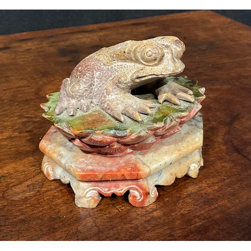 386 - A Chinese soapstone carving, of a toad, upon a lotus, octagonal base, 10cm wide