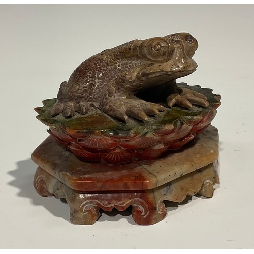 386 - A Chinese soapstone carving, of a toad, upon a lotus, octagonal base, 10cm wide