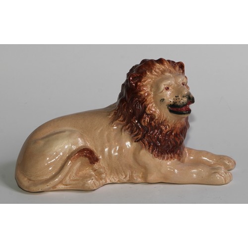 103 - An English pottery lion, modelled recumbent and slip cast, 21cm long