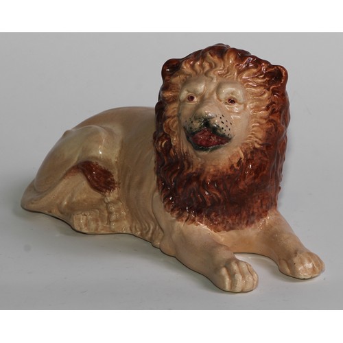 103 - An English pottery lion, modelled recumbent and slip cast, 21cm long