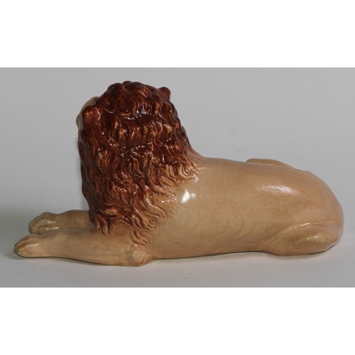 103 - An English pottery lion, modelled recumbent and slip cast, 21cm long