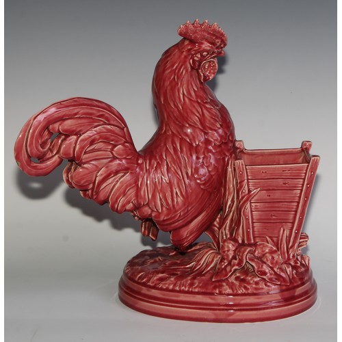 94 - A Majolica novelty vase, modelled as a cockerel beside a wooden planter, glazed in tones of pink, 38... 