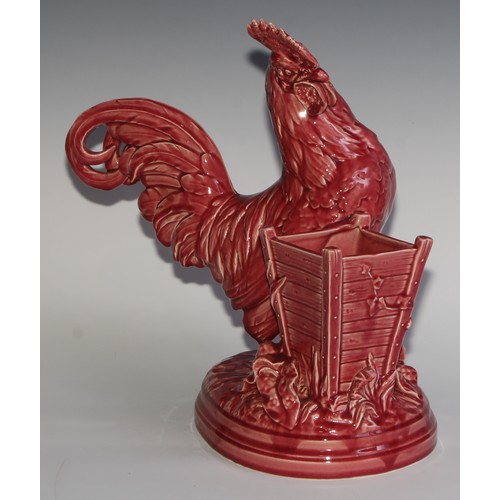 94 - A Majolica novelty vase, modelled as a cockerel beside a wooden planter, glazed in tones of pink, 38... 