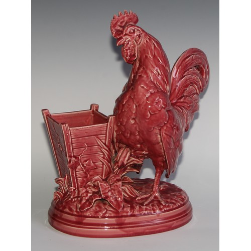 94 - A Majolica novelty vase, modelled as a cockerel beside a wooden planter, glazed in tones of pink, 38... 