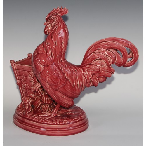 94 - A Majolica novelty vase, modelled as a cockerel beside a wooden planter, glazed in tones of pink, 38... 