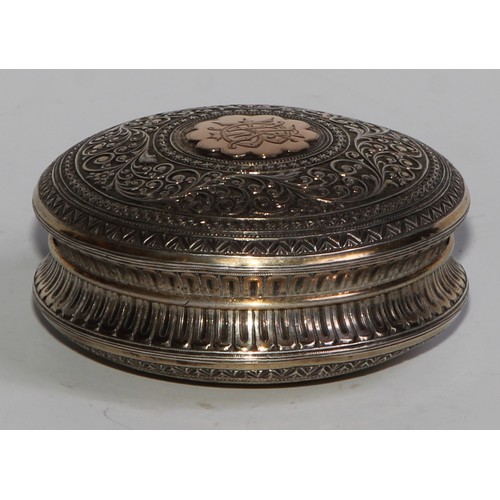 855 - A 19th century silver and gold coloured metal circular snuff box, chased overall in the Indian taste... 