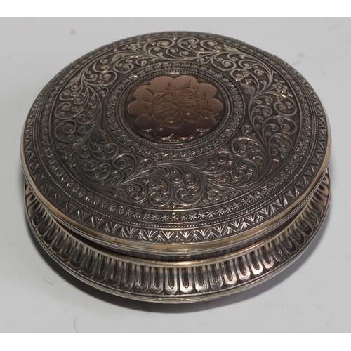 855 - A 19th century silver and gold coloured metal circular snuff box, chased overall in the Indian taste... 